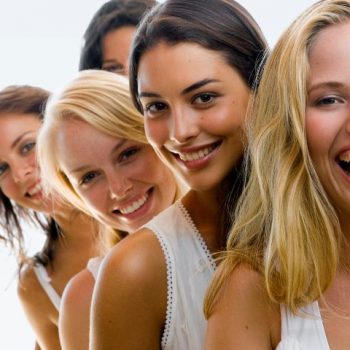 Jakie są fajne ciekawostki o kobietach? Na zdjęciu kilka uśmiechniętych kobiet w rzędzie pozuje do zdjęcia.