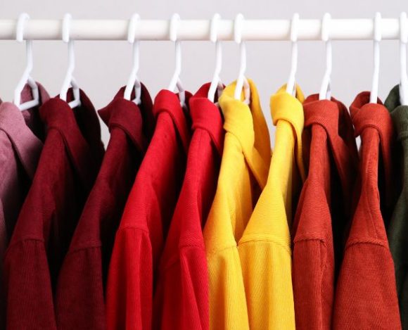 Kolorowe ubrania na wieszakach. Barwy odzieży odgrywają istotną rolę w psychologii ubioru.