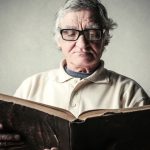 Starszy człowiek czyta książkę z cytatami o seniorach.