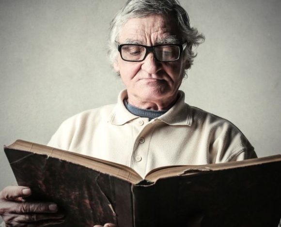 Starszy człowiek czyta książkę z cytatami o seniorach.