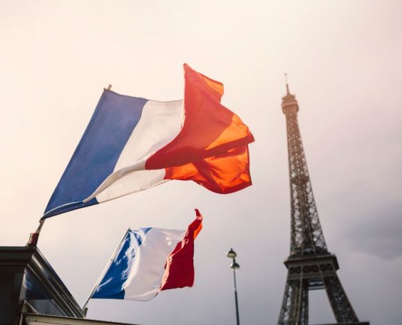 Ciekawostki o Francji – jednym z najstarszych państw Europy. Na zdjęciu flagi Francji na tle wieży Eiffla.