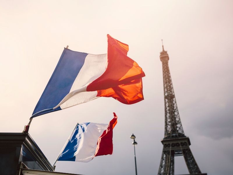 Ciekawostki o Francji – jednym z najstarszych państw Europy. Na zdjęciu flagi Francji na tle wieży Eiffla.
