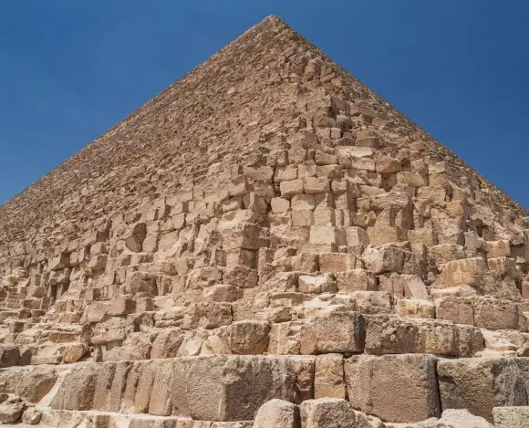 Piramida Cheopsa z bliska na tle błękitnego nieba.